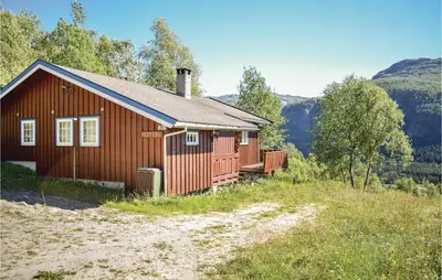 a red house on a hill with mountains in the background at Beitebu in Hemsedal