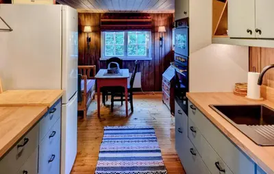 a kitchen with white cabinets and a table with a kitchen rug at Månebu in Nesbyen