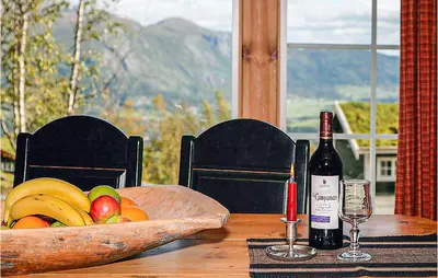 a wooden table with a bowl of fruit and a bottle of wine at Nice Home In Hemsedal With Sauna in Hemsedal