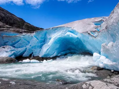 an ice cave in a river next to a glacier at Mlodge - The Mountain Lodge in Sogndal