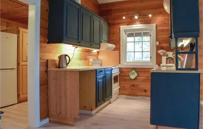 a kitchen with wooden walls and blue cabinets at Sundflathytta in Nesland