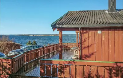 a wooden deck with a building next to the water at Holiday Home Vallersund Nausthylla Haldorhamn in Valsøya
