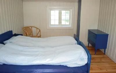 a bed in a bedroom with a blue dresser and a window at Haug Isakplassen in Steinkjer