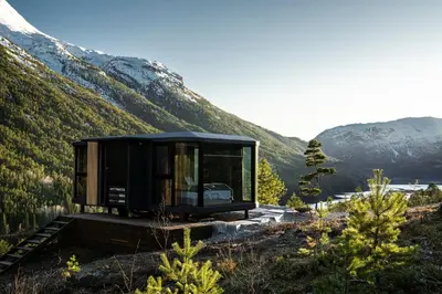 a black house on a hill with mountains in the background at Sogndal Fjordpanorama - The atmosphere in Sogndal