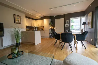 a living room with a table and chairs and a kitchen at Modern Apartment - Amazing Terrace and Fjord View, Close to City Center in Bergen