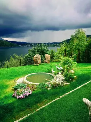 a garden with two chairs and a pond in the grass at Bergen sunrise Apartment - self check in - Free Parking in Bergen