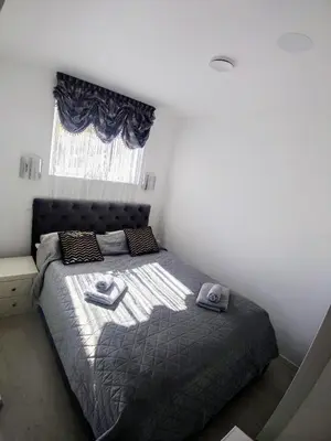 a bedroom with a bed with a gray comforter and a window at Bergen sunrise Apartment - self check in - Free Parking in Bergen