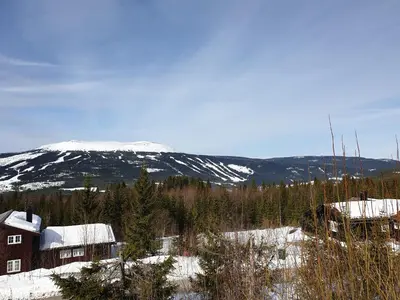 a house in the snow with a mountain in the background at ReveEnka - cabin in Trysil with Jacuzzi for rent in Trysil