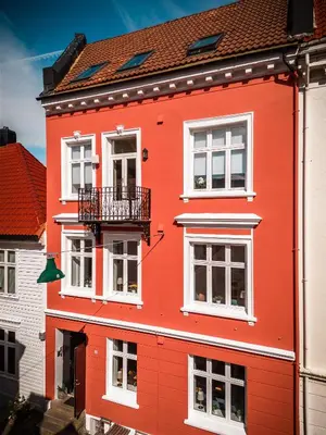 a red building with white windows and a balcony at Dragesmauet Apartments in Bergen