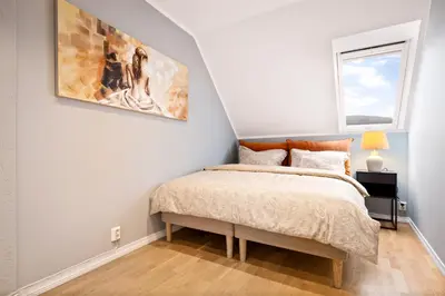 a bedroom with a bed and a painting on the wall at Dragesmauet Apartments in Bergen