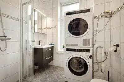 a washer and dryer in a bathroom with a sink at Rosen Apartment in Bergen