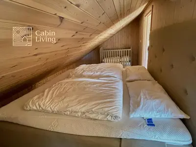 a bed in a wooden room with two pillows at New large cabin Ski in out Sjusjøen & sauna in Ringsaker