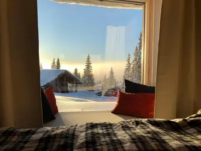 a bedroom window with a view of a snow covered yard at New large cabin Ski in out Sjusjøen & sauna in Ringsaker