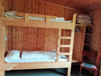 two bunk beds in a wooden room with a ladder at Lensmansgarden Fjøsen in Innfjorden