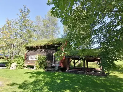 a house with a grass roof on a green field at Lensmansgarden Fjøsen in Innfjorden