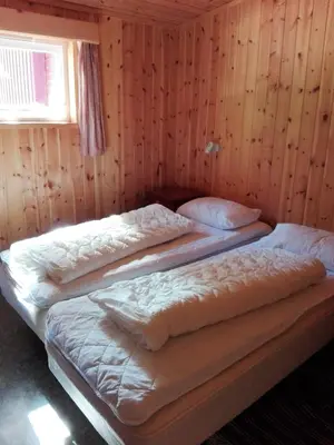 three beds in a room with wooden walls at Lensmansgarden Fjøsen in Innfjorden