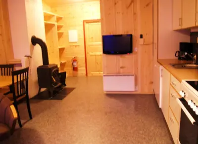 a kitchen with a refrigerator with a tv on it at Lensmansgarden Fjøsen in Innfjorden