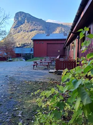 a group of picnic benches in front of a building at Lensmansgarden Fjøsen in Innfjorden