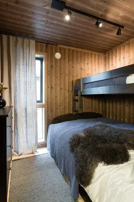 a bedroom with a bed in a wooden wall at Cozy modern holiday villa with electric car charging, sauna and fireplace in Øyer