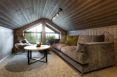 a living room with a couch and a table at Cozy modern holiday villa with electric car charging, sauna and fireplace in Øyer