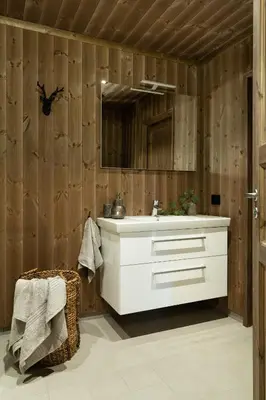 a bathroom with a white sink and wooden walls at Cozy modern holiday villa with electric car charging, sauna and fireplace in Øyer