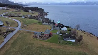 an island with houses and a windmill in the water at Fjord side apartment in Jondal