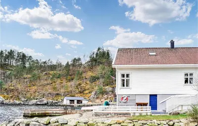 a white house next to a body of water at Cozy Home In Vanvik With Wifi in Vanvik