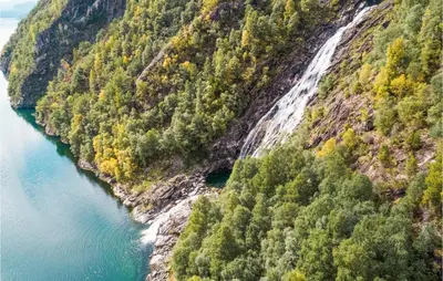 a waterfall on the side of a mountain next to a river at Cozy Home In Vanvik With Wifi in Vanvik