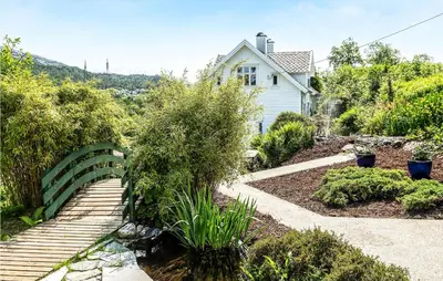 a garden with a green fence and a house at Amazing Home In Skjoldastraumen in Skjoldastraumen