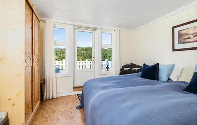 a bedroom with a blue bed and a balcony at Amazing Home In Skjoldastraumen in Skjoldastraumen
