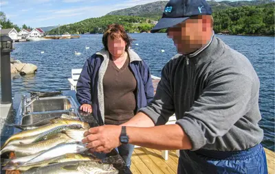 a man and a woman holding a large fish on a boat at Amazing Home In Skjoldastraumen in Skjoldastraumen