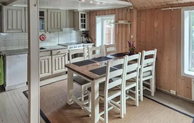 a kitchen with a wooden table and some white cabinets at Lovely Home In Bjoa With Kitchen in Utbjoa