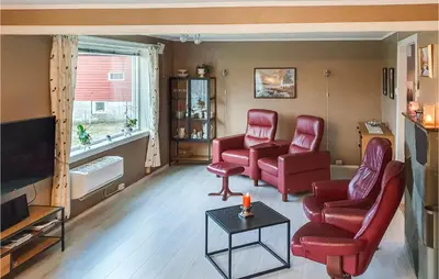 a living room with red chairs and a tv at 5 Bedroom Lovely Home In Bjoa in Utbjoa