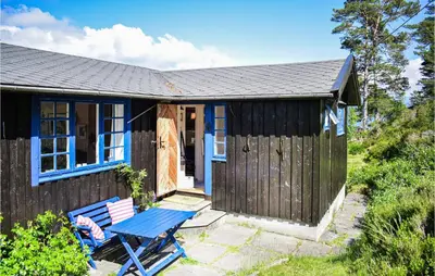 a blue cottage with a picnic table and a bench at Gorgeous Home In Reksteren With Kitchen in Klinkholmen