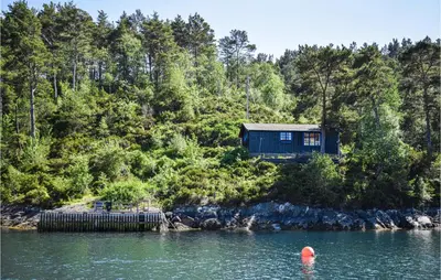 a blue house on the shore of a body of water at Gorgeous Home In Reksteren With Kitchen in Klinkholmen