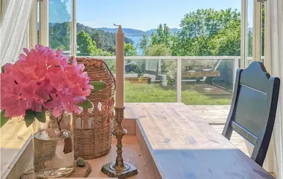 a table with a vase of pink flowers on a porch at Lovely Home In Fjelberg With Wifi in Sæbø