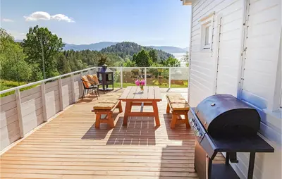 a deck with a grill and picnic tables on a house at Lovely Home In Fjelberg With Wifi in Sæbø