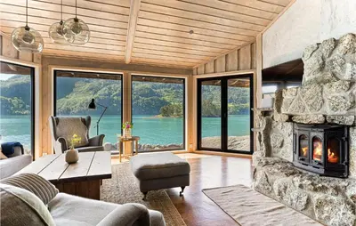 a living room with a stone fireplace with a view of the water at Sjøbris in Erve