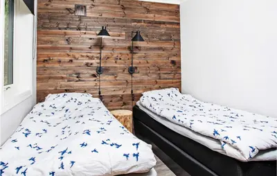 a bedroom with two beds and a wooden wall at Sjøbris in Erve