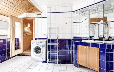 a blue tiled bathroom with a washing machine in it at Awesome Home In Etne With Sauna in Erve