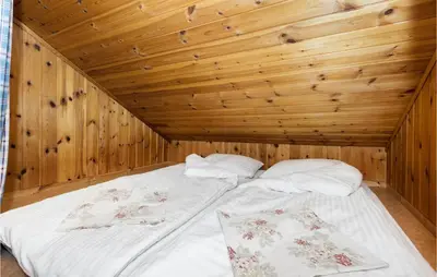 a bed in a room with a wooden ceiling at Cozy Home In Norheimsund With Sauna in Norheimsund