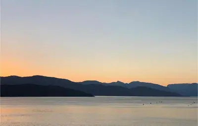 a sunset over the water with mountains in the background at Beautiful Home In Jondal in Jondal