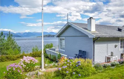 a house with flowers in front of a body of water at Beautiful Home In Jondal in Jondal