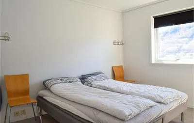 a bed in a room with two chairs and a window at 3 Bedroom Amazing Home In Norheimsund in Norheimsund