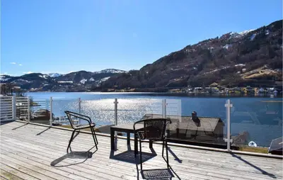 a table and chairs on a deck with a view of a lake at 3 Bedroom Amazing Home In Norheimsund in Norheimsund