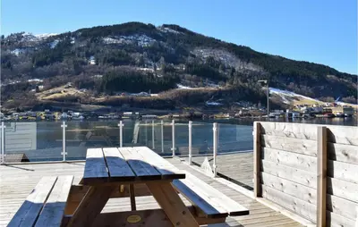 a wooden bench sitting on a dock next to the water at 3 Bedroom Amazing Home In Norheimsund in Norheimsund