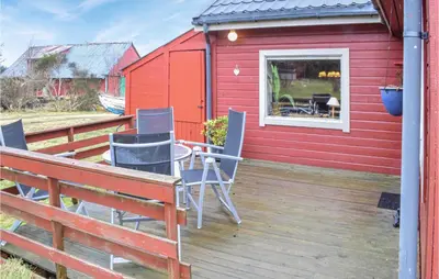 a red house with chairs and a table on a deck at Amazing Home In Fonnes With Wifi in Fonnes