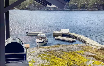 two boats are docked at a dock on a lake at 3 Bedroom Stunning Home In Masfjorden in Masfjorden