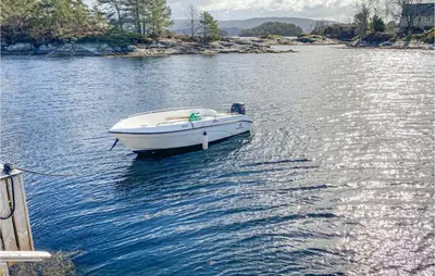 a white boat tied to a dock on a lake at 3 Bedroom Stunning Home In Masfjorden in Masfjorden