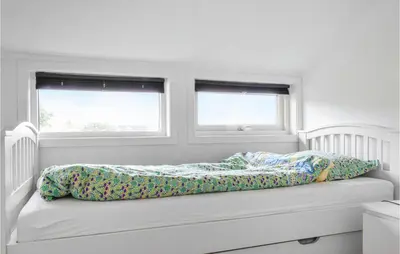 a bed in a white room with two windows at Gorgeous Home In Stolmen With Kitchen